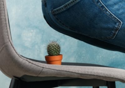 Woman sitting down on chair with cactus on seat
